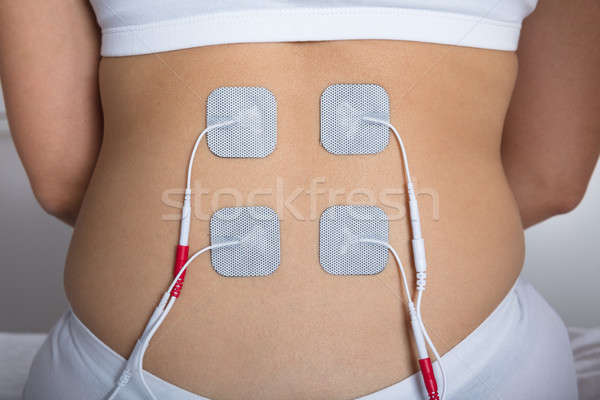 Woman With Electrostimulator Electrodes On Her Back Stock photo © AndreyPopov