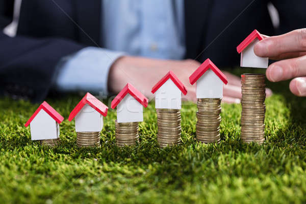 Businessperson Arranging House Model Over Stacked Coins Stock photo © AndreyPopov