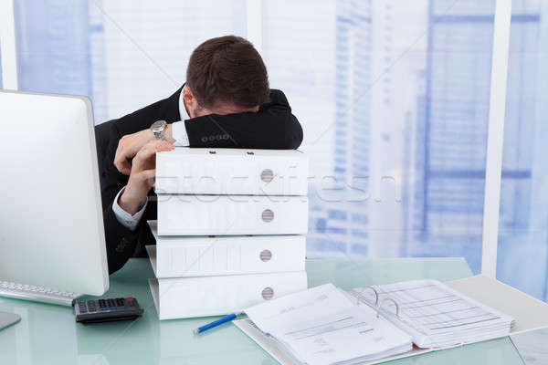 Stressed Businessman Resting Head On Binders At Desk Stock photo © AndreyPopov