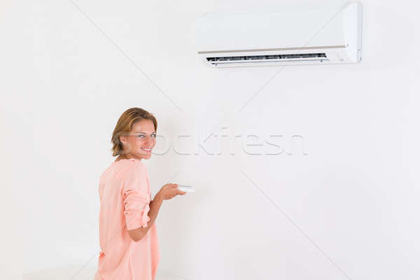 Woman Operating Air Conditioner Stock photo © AndreyPopov