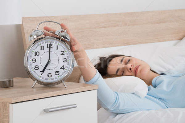 Woman Turning Off Alarm While Sleeping On Bed Stock photo © AndreyPopov