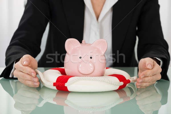 Businesswoman Hand Protecting Piggybank With Lifebelt Stock photo © AndreyPopov