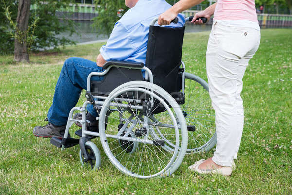 Woman Assisting Disabled Man On Wheelchair Stock photo © AndreyPopov