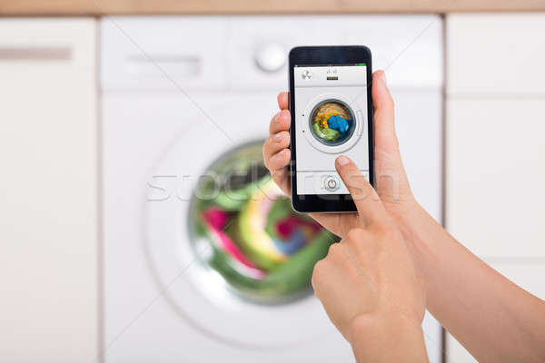 Woman Using Mobile Phone To Operate Washing Machine Stock photo © AndreyPopov