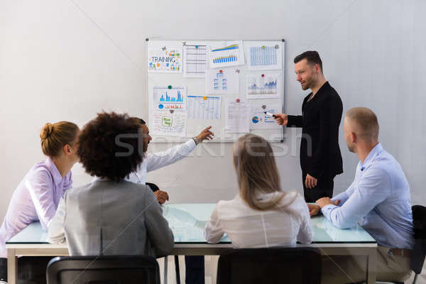 Zakenman uitleggen grafieken collega's jonge werkplek Stockfoto © AndreyPopov
