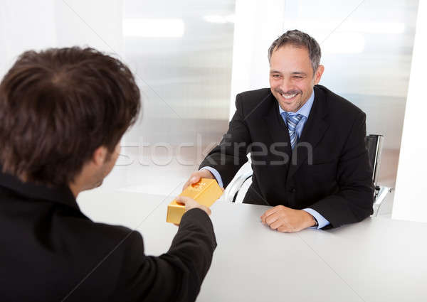 Businessman receiving gold bar Stock photo © AndreyPopov
