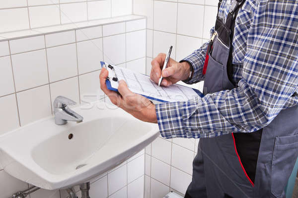 Plumber Standing In Front Of Washbasin Writing On Clipboard Stock photo © AndreyPopov