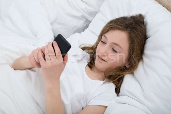 Girl With Mobile Phone In Bedroom Stock photo © AndreyPopov