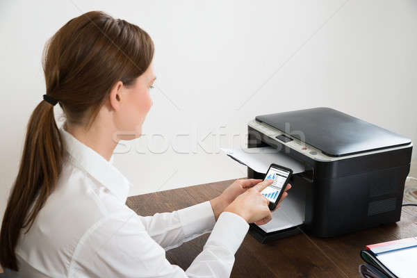 Businesswoman With Mobile Phone Connected To Printer Stock photo © AndreyPopov