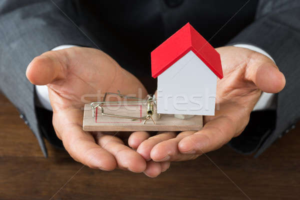 Businessman Holding Model House On Rattrap Stock photo © AndreyPopov