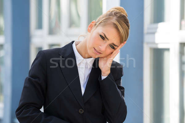 Stock photo: Sad Businesswoman Touching Head Against Buildings