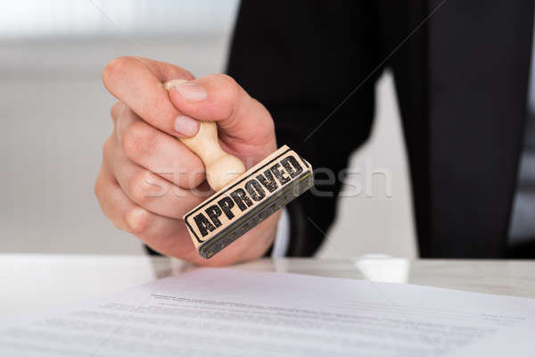 Stock photo: Businesswoman Stamping Approved On Contract Paper At Desk