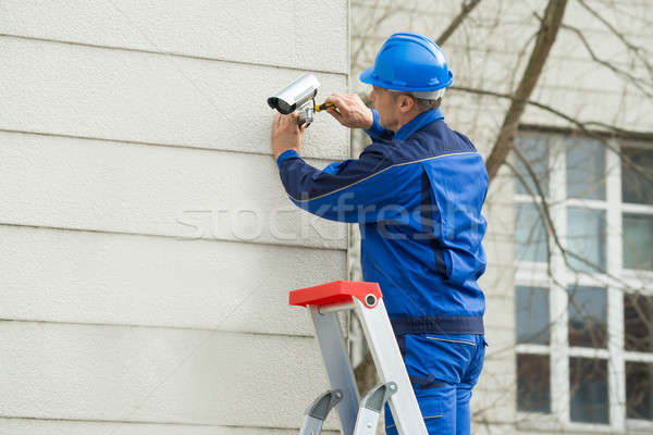 Male Technician Standing On Stepladder Fitting CCTV Camera Stock photo © AndreyPopov