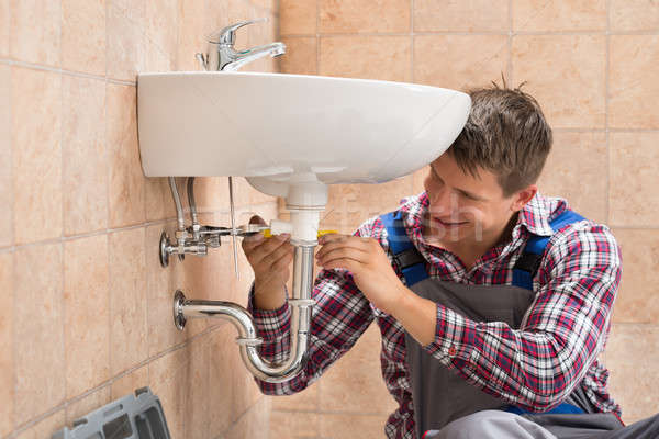 Foto stock: Sorridente · encanador · afundar · masculino · banheiro