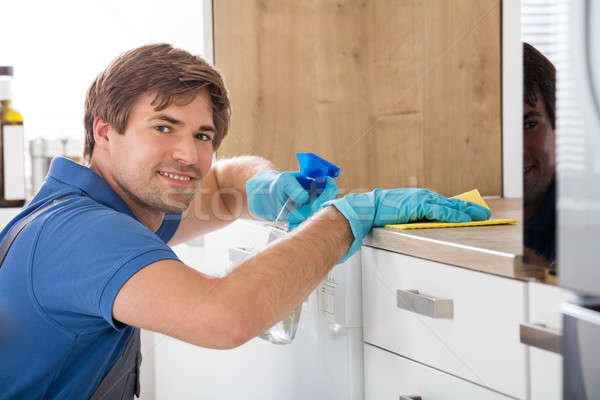 Male Worker Holding Bottle Spray And Cleaning Countertop Stock photo © AndreyPopov