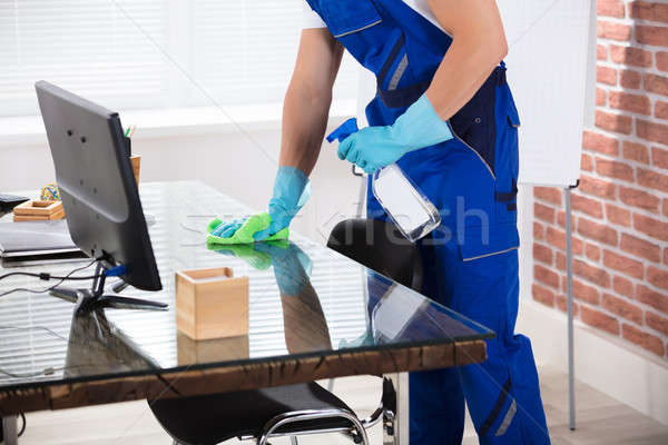 Janitor Cleaning Desk With Cloth In Office Stock photo © AndreyPopov