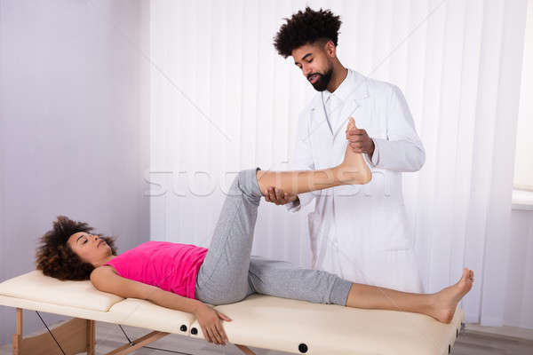 Physiotherapist Giving Leg Exercise To Patient Stock photo © AndreyPopov