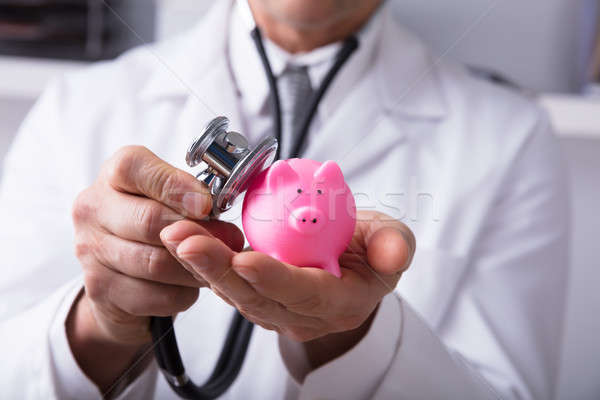 Doctor Checking Piggybank With Stethoscope Stock photo © AndreyPopov
