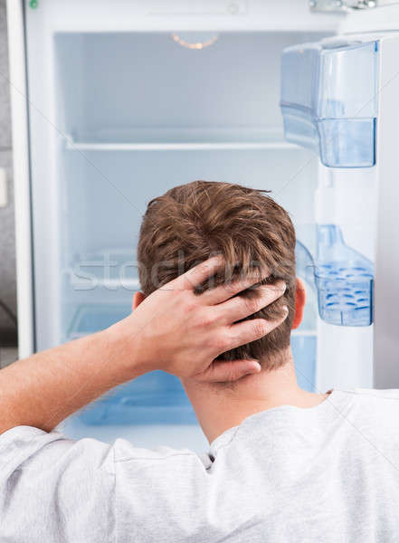 Stock photo: Thoughtful man looking in empty refrigerator