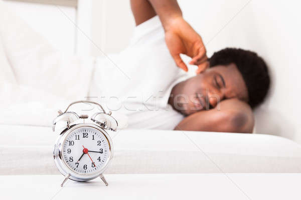 Stock photo: Frustrated Man In Front Of Alarm Clock
