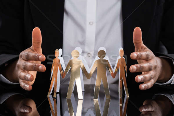 Businessperson Protecting Cut-out Figures Stock photo © AndreyPopov