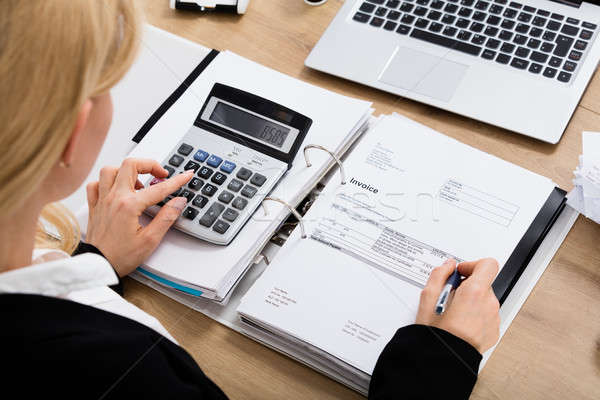 Stock photo: Businesswoman Calculating Invoice In Office