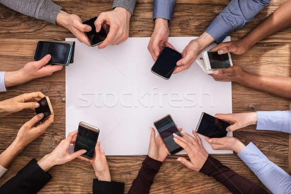 Elevated View Of Businesspeople Hand Using Mobile Phone Stock photo © AndreyPopov