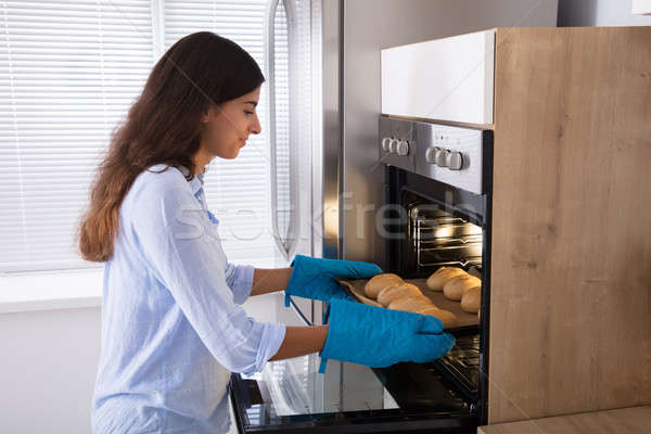Woman Taking Out Tray Of Baked Bread From Oven Stock photo © AndreyPopov