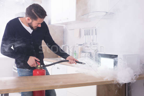 Hombre extintor de incendios microonda horno joven cocina Foto stock © AndreyPopov