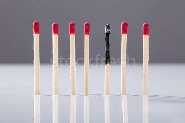 Burnt Matchstick Separated By Red Matchsticks Stock photo © AndreyPopov