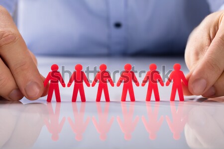 Businesswoman Holding Team Of Paper People At Desk Stock photo © AndreyPopov