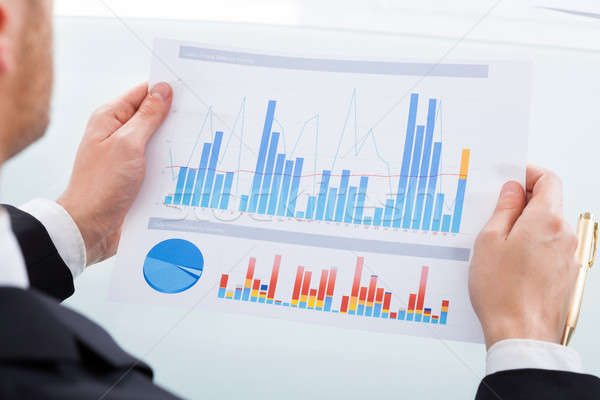 Businessman Comparing Graphs At Office Desk Stock photo © AndreyPopov