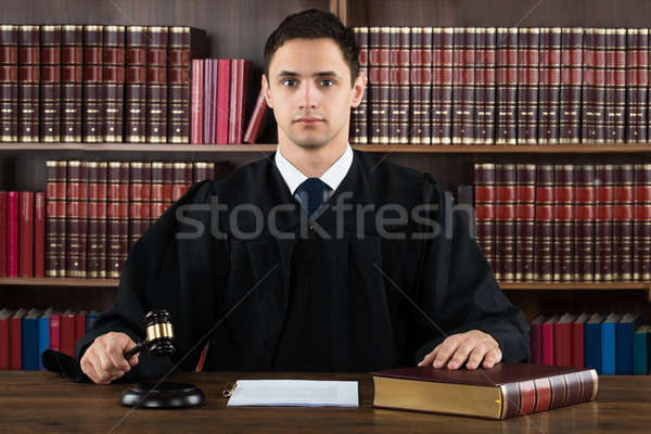 Stock photo: Portrait Of Confident Judge Hitting Mallet At Desk