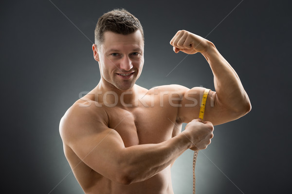Happy Muscular Man Measuring Bicep With Measure Tape Stock photo © AndreyPopov