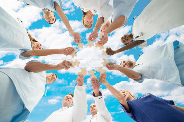 Medical Team Joining Jigsaw Pieces Against Sky Stock photo © AndreyPopov