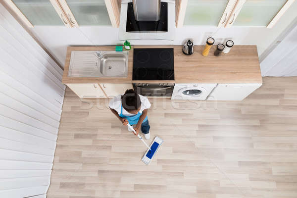 Stock photo: Female Janitor Cleaning Floor In Kitchen