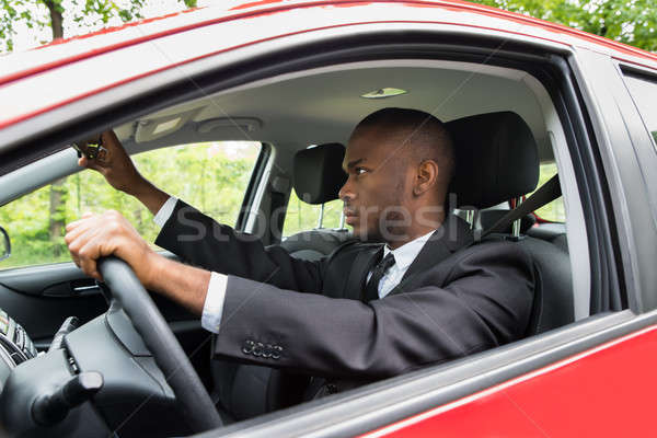 Businessman Adjusting Mirror While Driving Car Stock photo © AndreyPopov