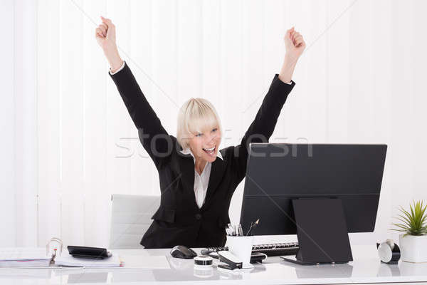 Happy Businesswoman Raising Arms At Desk Stock Photo C Andriy