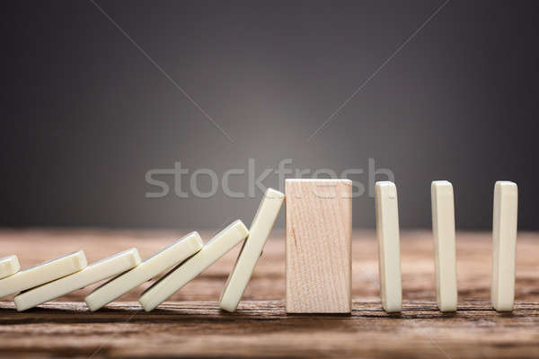 Wooden Block Amidst Falling And Upright Domino Pieces On Table Stock photo © AndreyPopov