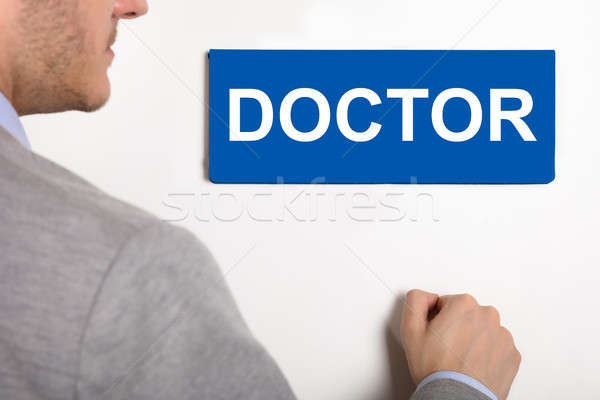 Businessman Knocking Door With Doctor Nameplate Stock photo © AndreyPopov