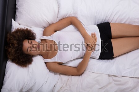 Mujer sufrimiento estómago dolor cama Foto stock © AndreyPopov