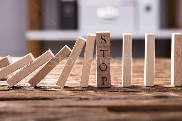 Falling Dominos Stopped By Wooden Blocks Showing Stop Text Stock photo © AndreyPopov