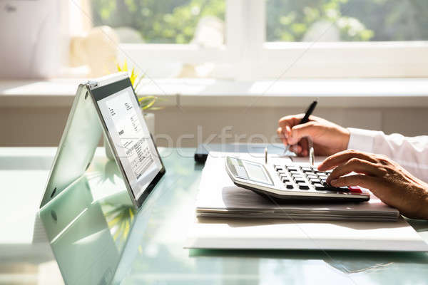 Businessman calculating invoice using calculator Stock photo © AndreyPopov