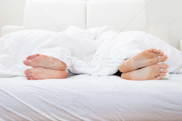 Close-up of couple's feet sleeping on bed Stock photo © AndreyPopov