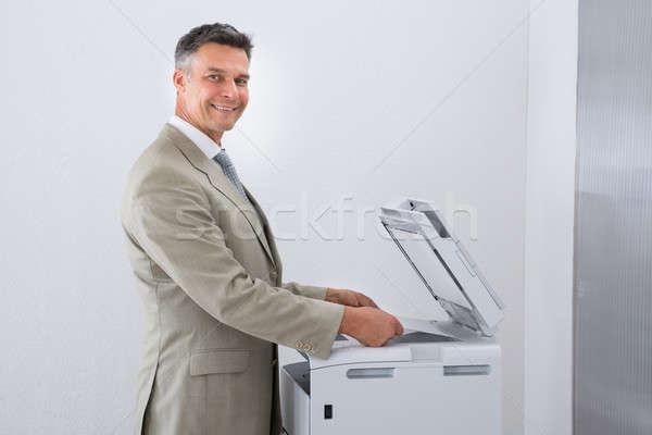 Businessman Keeping Paper On Photocopy Machine In Office Stock photo © AndreyPopov