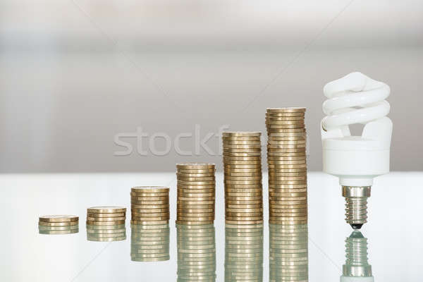 Fluoreszkáló villanykörte egymásra pakolva érmék asztal közelkép Stock fotó © AndreyPopov