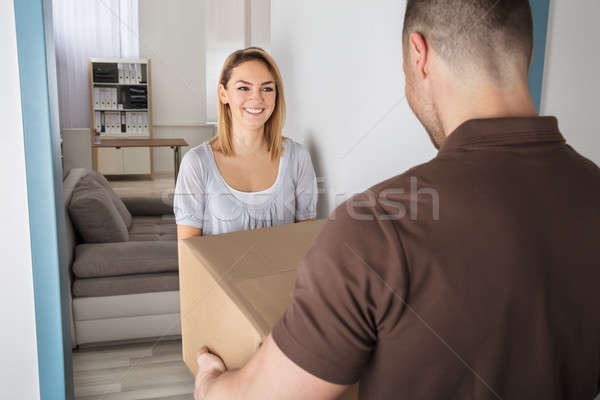 Stock photo: Delivery Man Giving Parcel Box To Young Woman