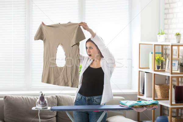 Woman Looking At Burnt T-shirt At Home Stock photo © AndreyPopov