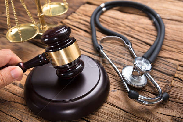 Judge's Hand Hitting Mallet By Stethoscope And Justice Scale Stock photo © AndreyPopov