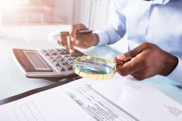 Businessman Holding Magnifying Glass Over Invoice Stock photo © AndreyPopov